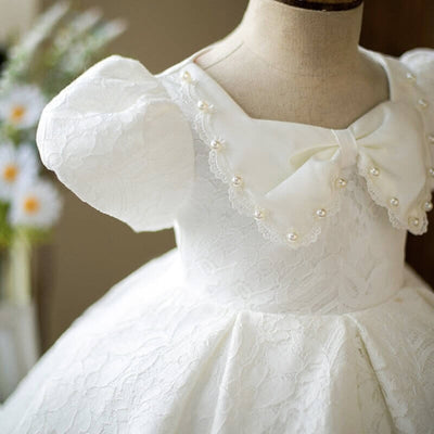 Robe baptême bébé fille blanche en dentelle avec nœud en satin et manches bouffantes