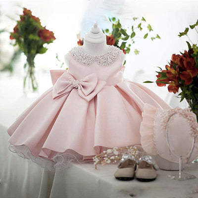Robe baptême bébé fille rose pâle avec col orné de perles et nœud décoratif